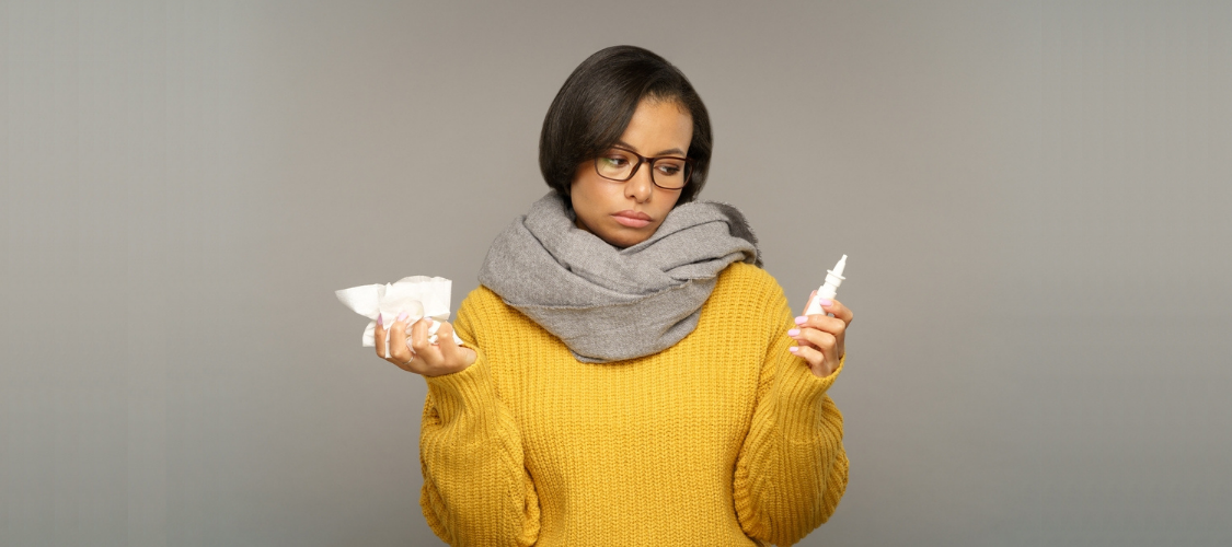 Women with Sinus Issues Holding Decongestant Spray and Tissues